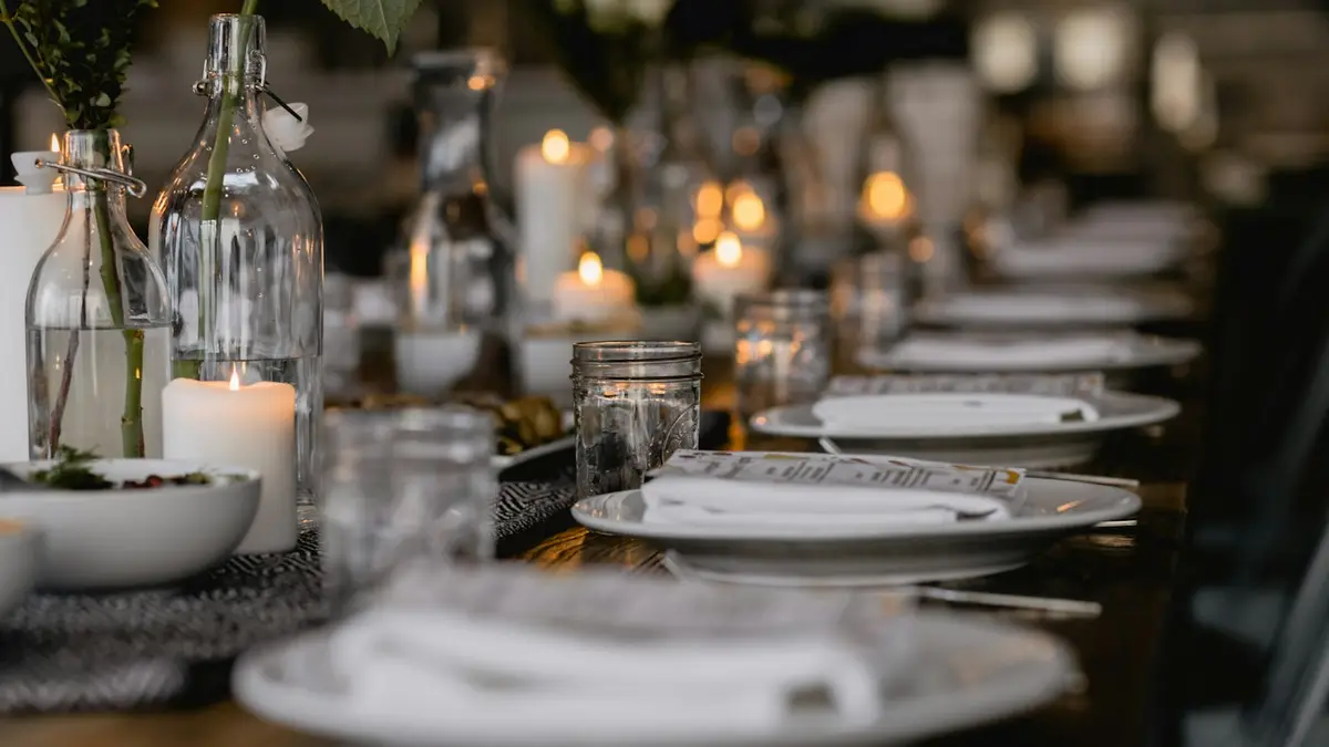 A long dining table set with plates, glasses and candles