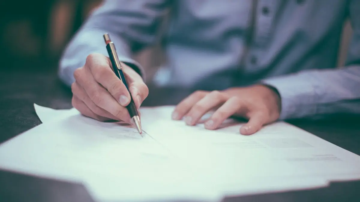 A person signing a document at a desk